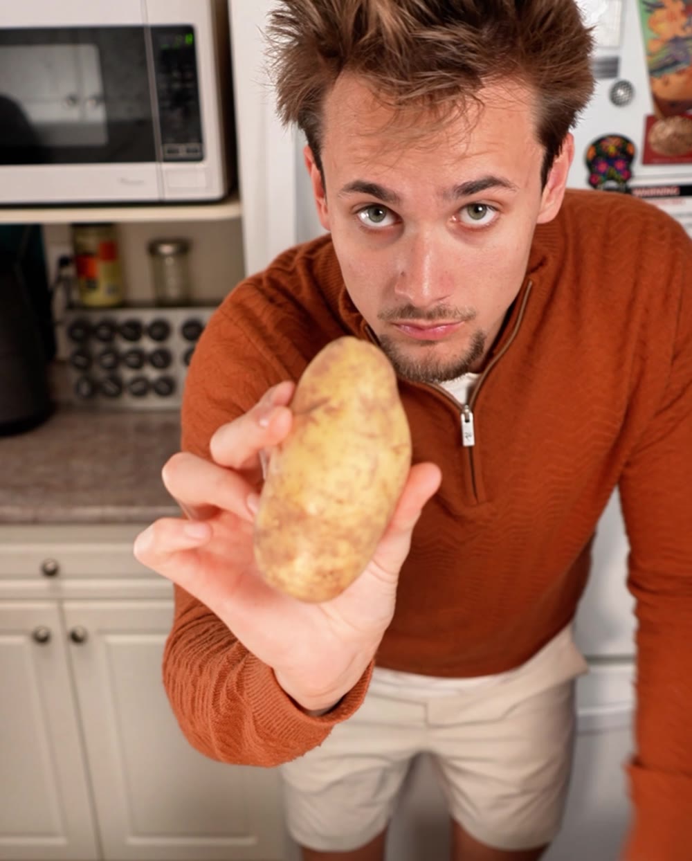 Jack Tysowski in a rust quarter-zip holding a potato toward the camera