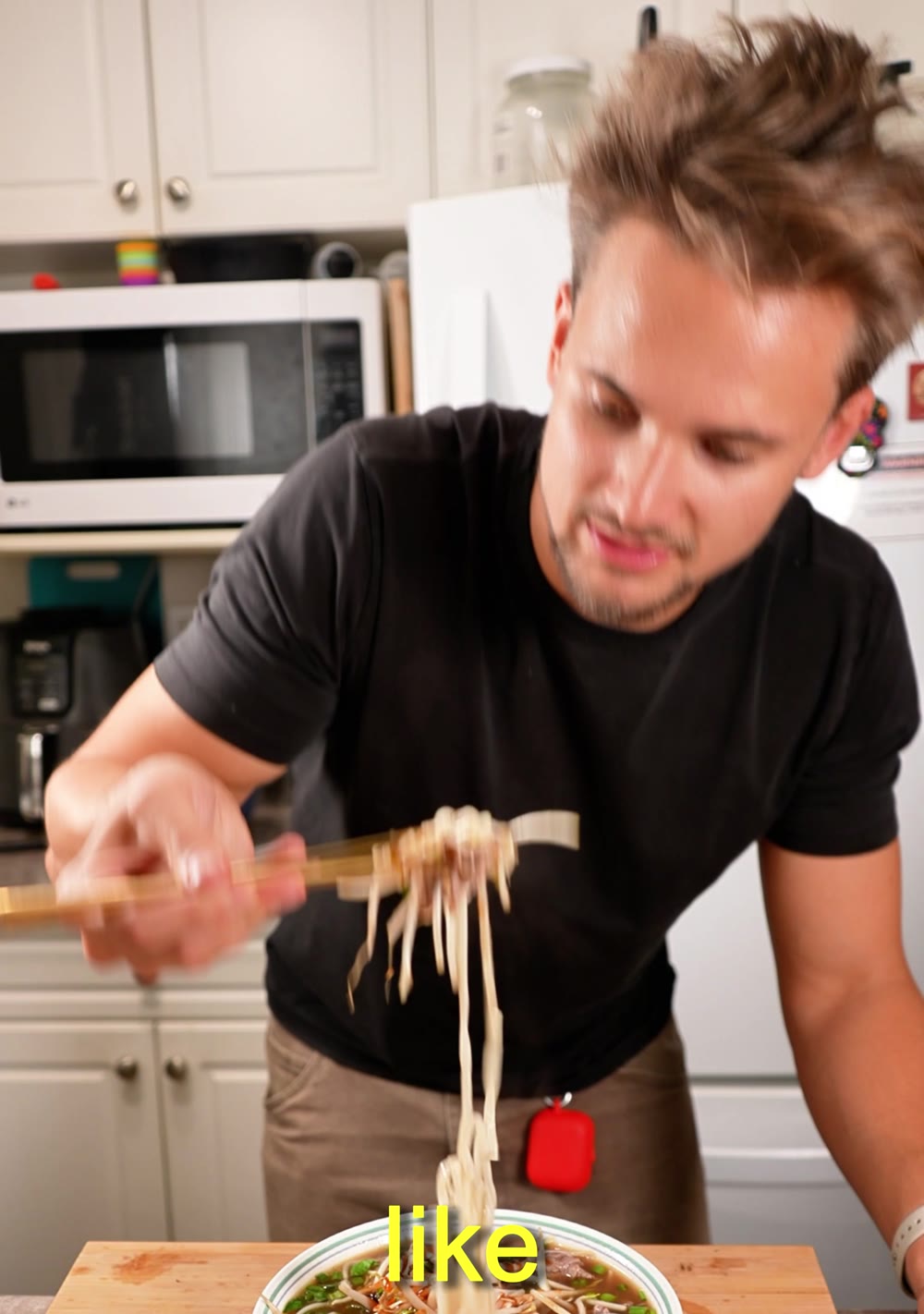 Jack lifting pho noodles out of the bowl with chopsticks